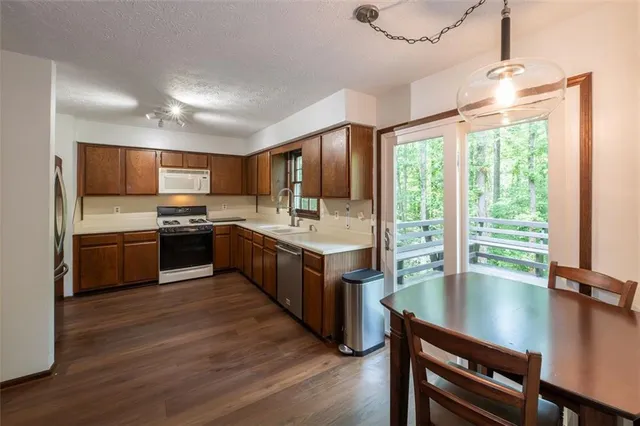 a kitchen with stainless steel appliances granite countertop a stove top oven a sink dishwasher a dining table and chairs with wooden floor