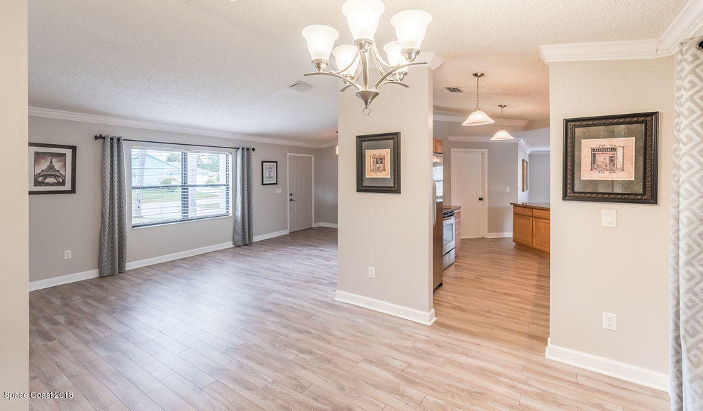 731 Raleigh Road Southeast Palm Bay, FL 32909 - Photo 12 of 36 a view interior of a house with wooden floor windows and a chandelier
