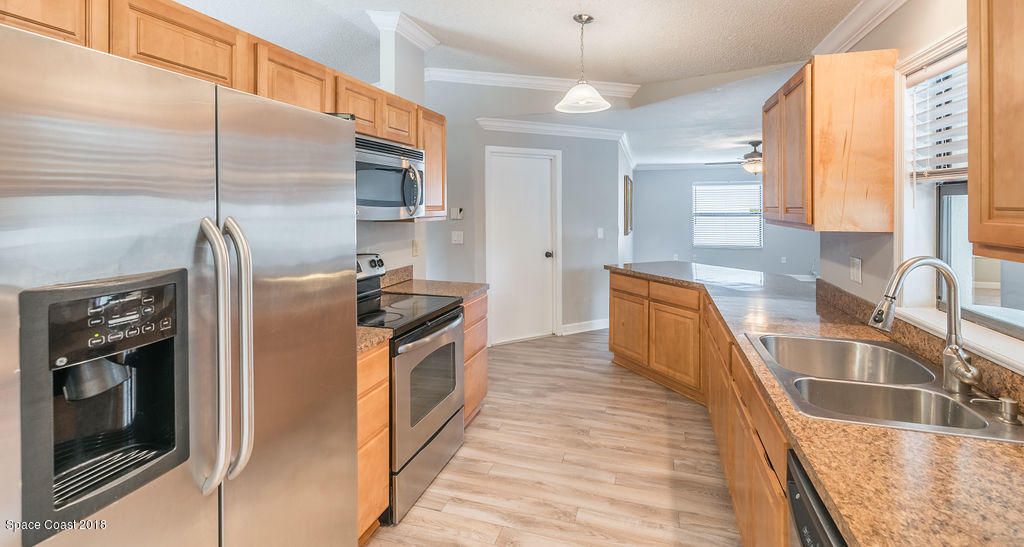 731 Raleigh Road Southeast Palm Bay, FL 32909 - Photo 13 of 36 a kitchen with stainless steel appliances granite countertop a refrigerator a stove and a sink with wooden floor