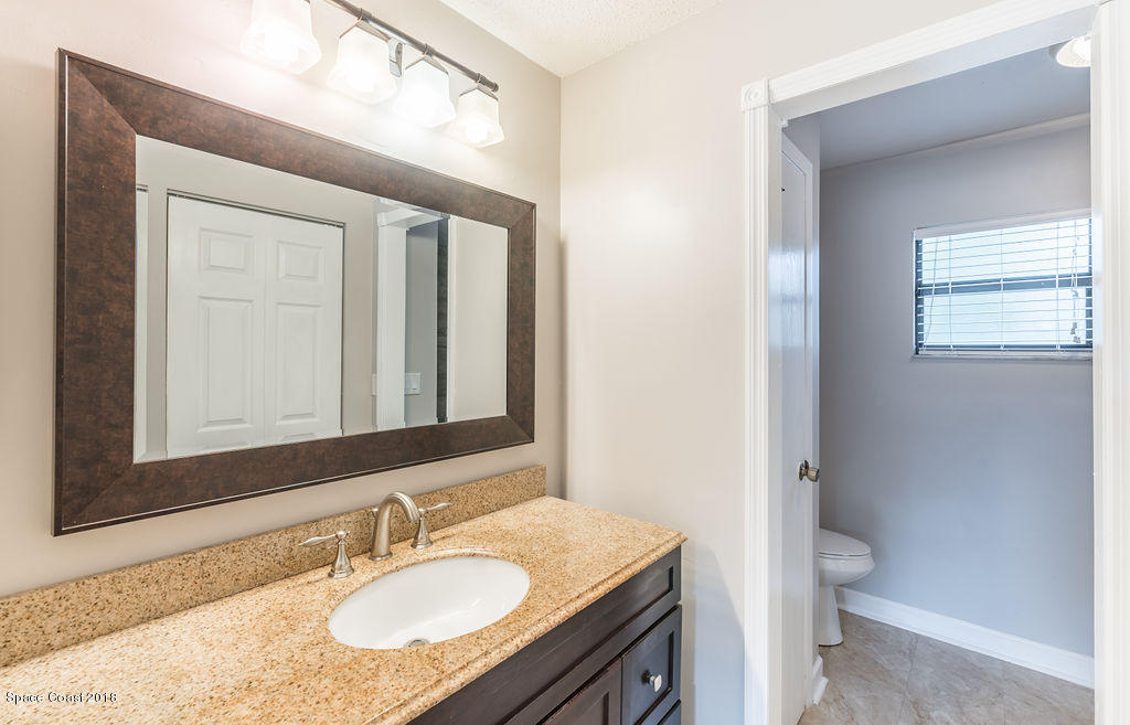 731 Raleigh Road Southeast Palm Bay, FL 32909 - Photo 22 of 36 a bathroom with a granite countertop sink toilet and mirror