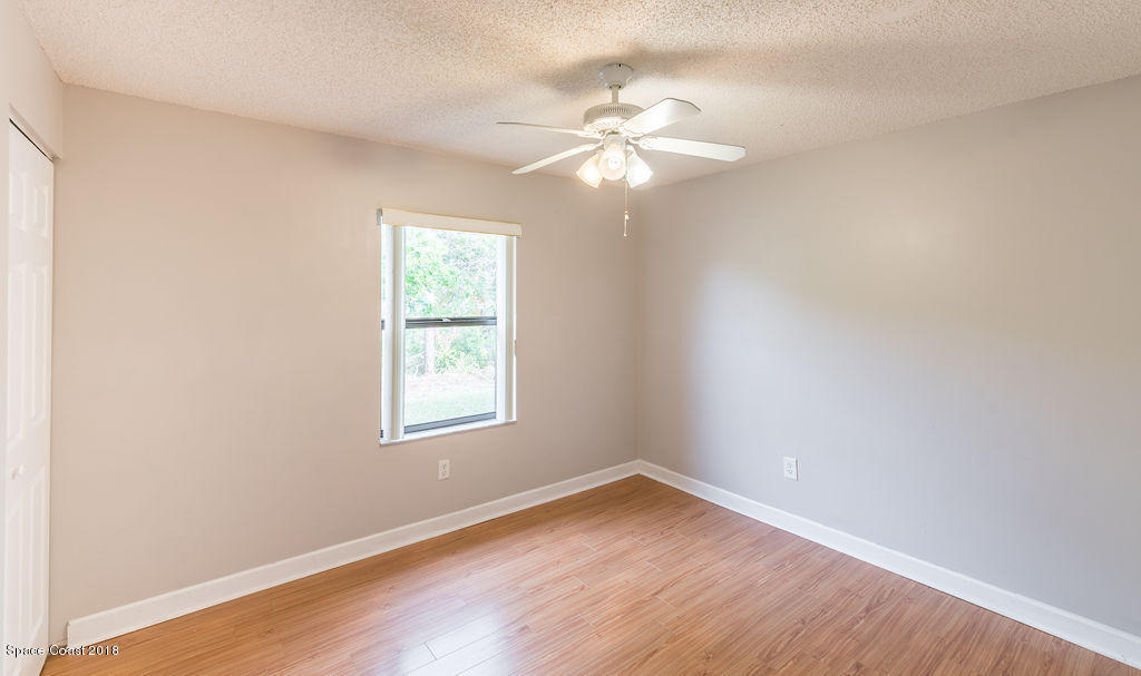 731 Raleigh Road Southeast Palm Bay, FL 32909 - Photo 25 of 36 an empty room with wooden floor fan and windows