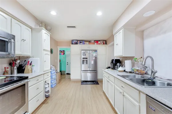 a kitchen with refrigerator a stove top oven a sink and dishwasher with wooden floor