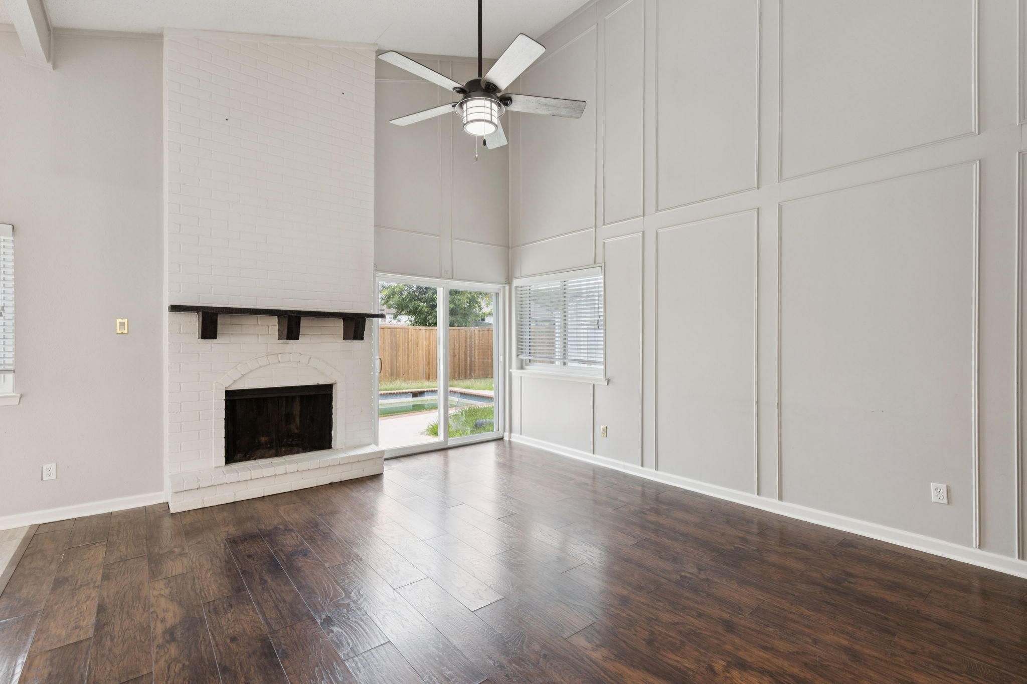 910 Via Valencia Mesquite, TX 75150 - Photo 7 of 23 an empty room with wooden floor a ceiling fan a fireplace and windows