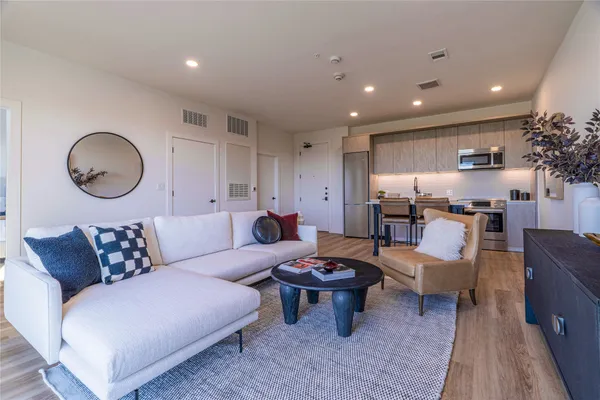 a living room with furniture kitchen view and a potted plant