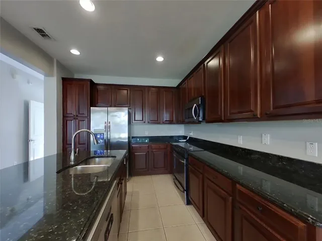 a kitchen with stainless steel appliances granite countertop a sink stove and refrigerator