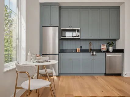 a kitchen with stainless steel appliances a white table and chairs in it