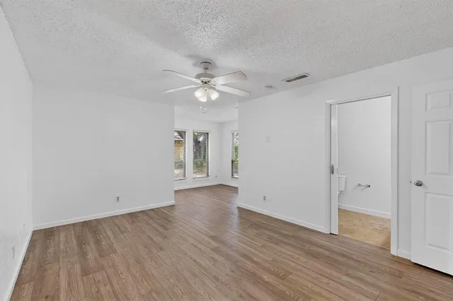 an empty room with wooden floor and ceiling fan