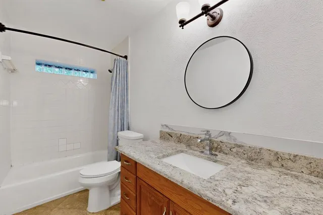a bathroom with a granite countertop sink toilet and a mirror