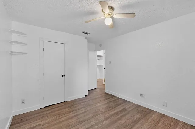 an empty room with wooden floor and fan