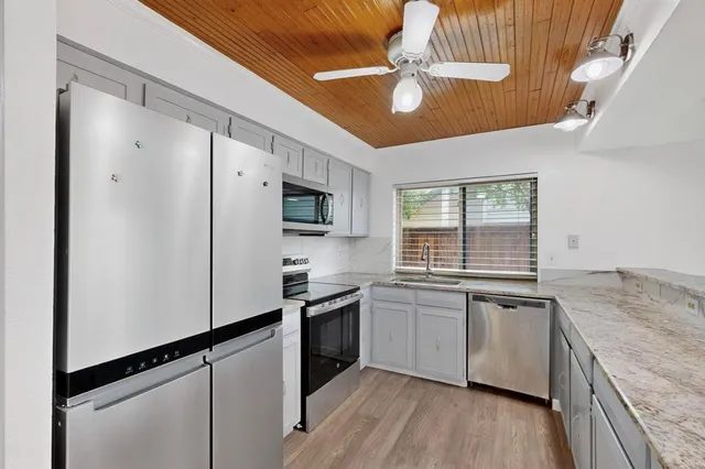 a kitchen with stainless steel appliances granite countertop a sink a stove and refrigerator