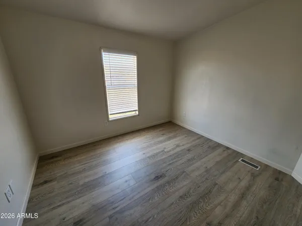 a view of an empty room with wooden floor and windows