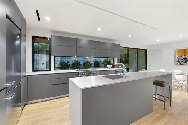 a view of living room with stainless steel appliances granite countertop a sink and a large window