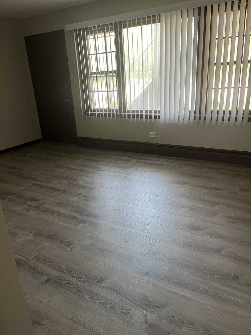 7831 Roberts Road, Unit 3 Bridgeview, IL 60455 - Photo 3 of 7 an empty room with wooden floor and windows