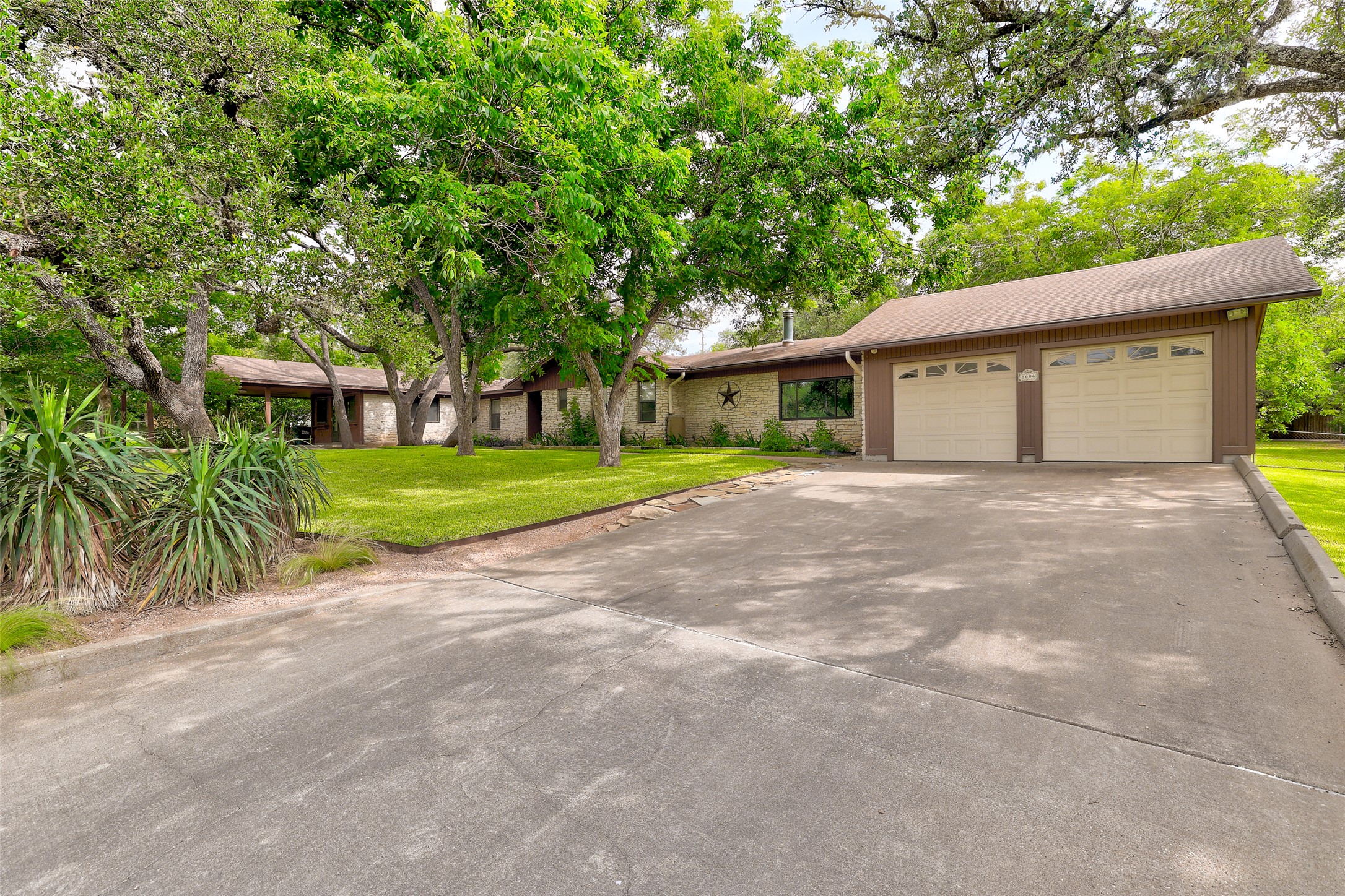 8606 Thunderbird Road, Unit A & B Austin, TX 78736 - Photo 27 of 34 Mature trees shade this inviting ranch-style home, featuring a prominent two-car garage and manicured front lawn.