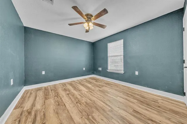 a view of a room with a ceiling fan and wooden floor