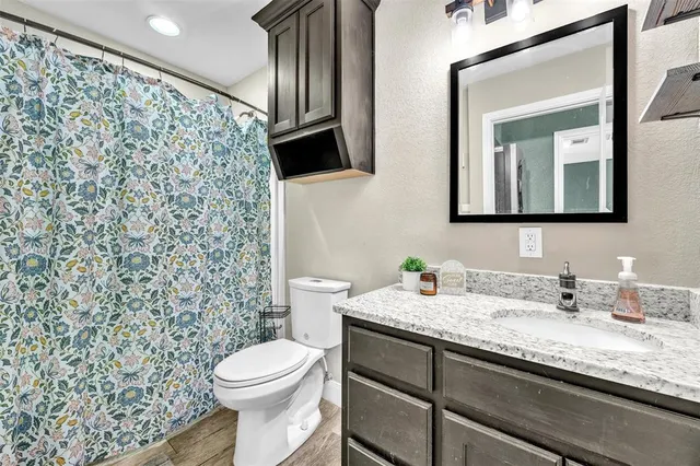 a bathroom with a granite countertop toilet sink and mirror