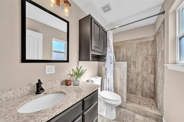 a bathroom with a granite countertop sink toilet and shower
