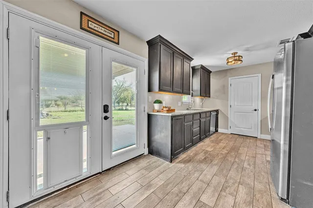 a kitchen with granite countertop a refrigerator a sink dishwasher a stove and white cabinets with wooden floor