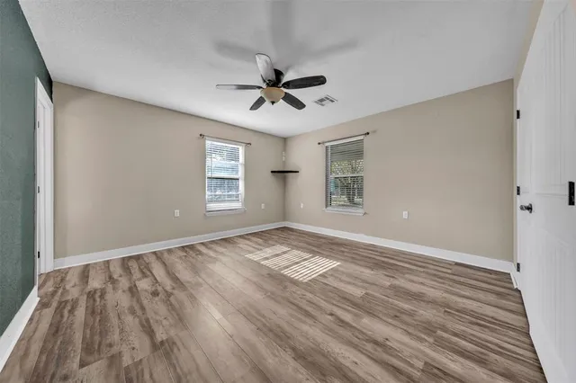 a view of an empty room with a window and wooden floor