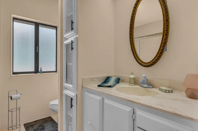 a bathroom with a granite countertop toilet sink and mirror