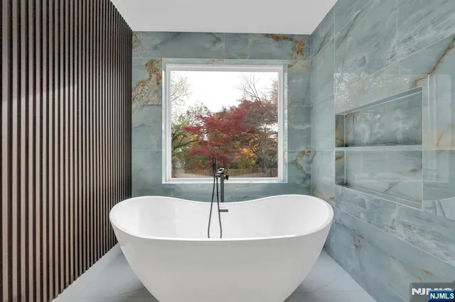 a white bath tub sitting in a bathroom next to a window
