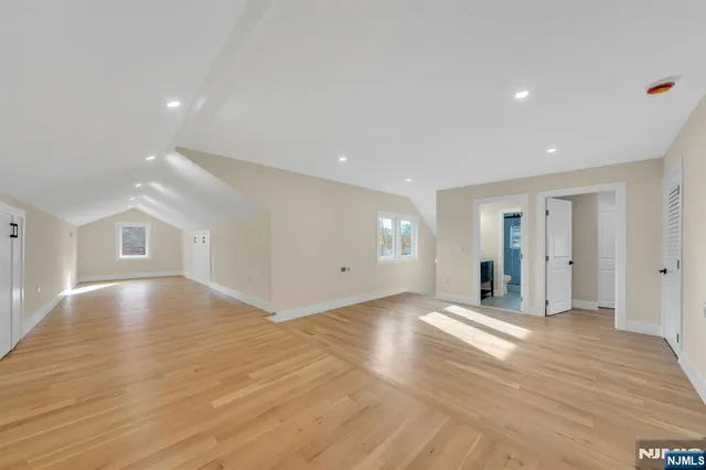 a view of an empty room with wooden floor and closet
