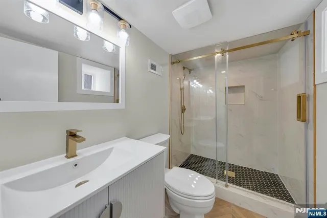 a bathroom with a sink a toilet a glass door shower and a mirror