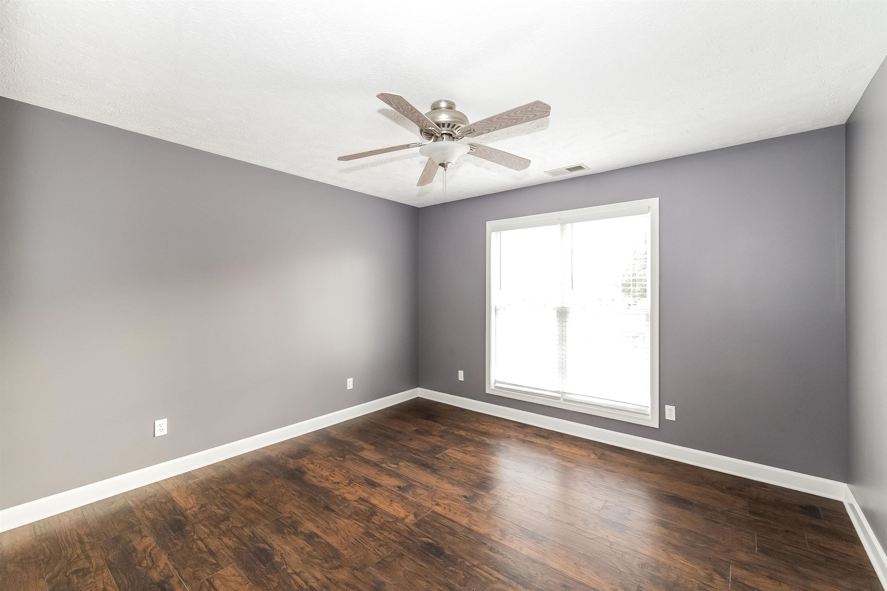 97 Jadewood Drive Jackson, TN 38305 - Photo 11 of 16 an empty room with wooden floor ceiling fan and windows