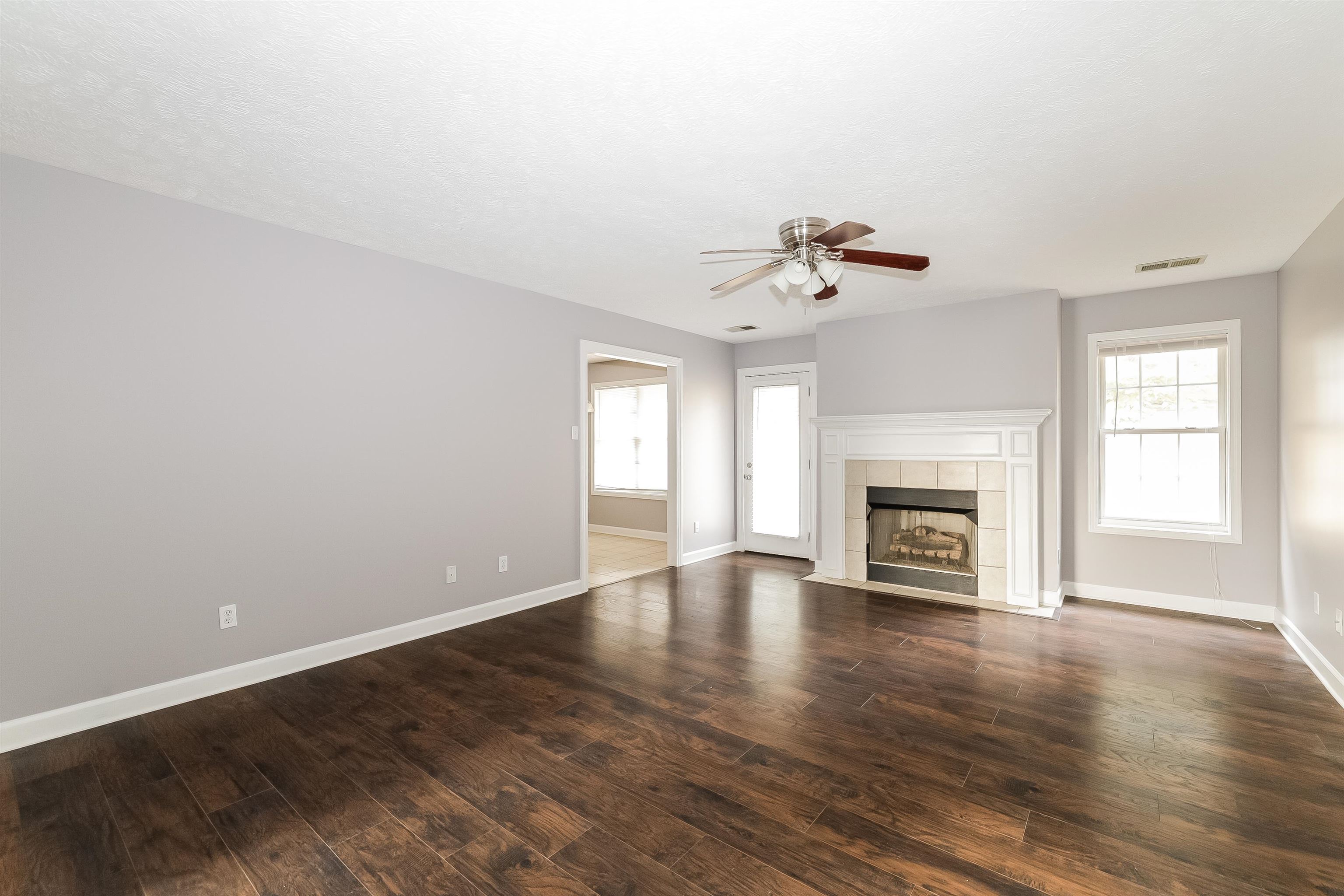 97 Jadewood Drive Jackson, TN 38305 - Photo 2 of 16 an empty room with wooden floor fireplace and window