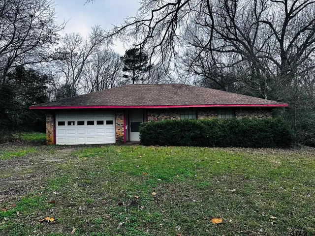 a view of a house with a yard potted plants and large trees