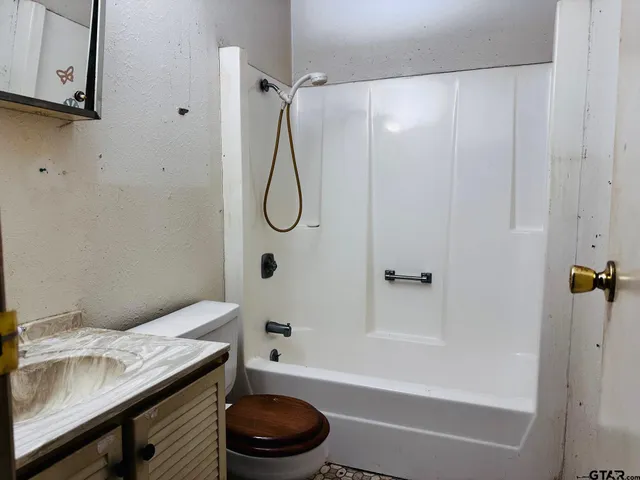 a bathroom with a granite countertop bathtub sink vanity and toilet