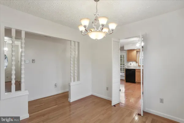 a view of an empty room with wooden floor and a kitchen