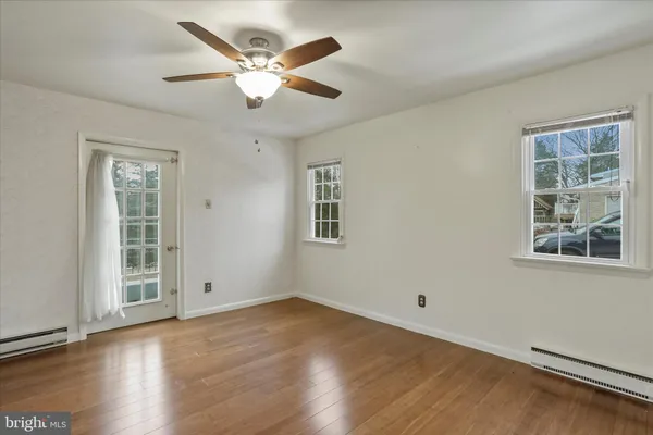 a view of an empty room with wooden floor and a window