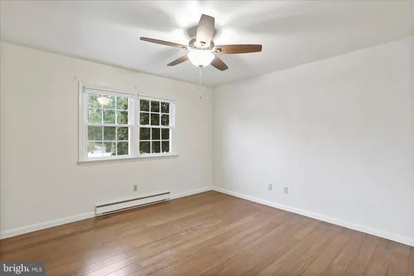 an empty room with wooden floor fan and windows