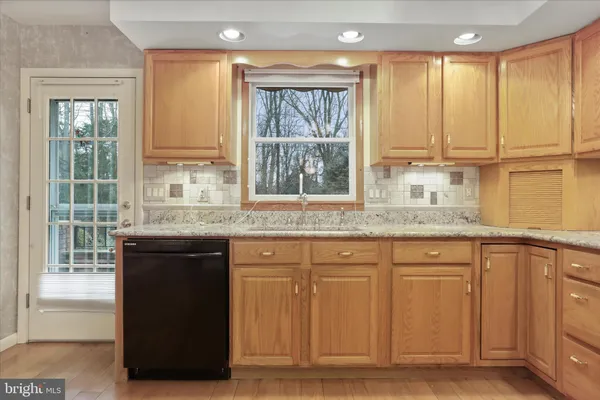 a kitchen with granite countertop a stove a sink wooden cabinets and a window