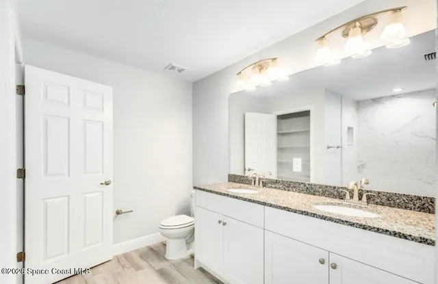 a bathroom with a granite countertop sink a toilet and a mirror