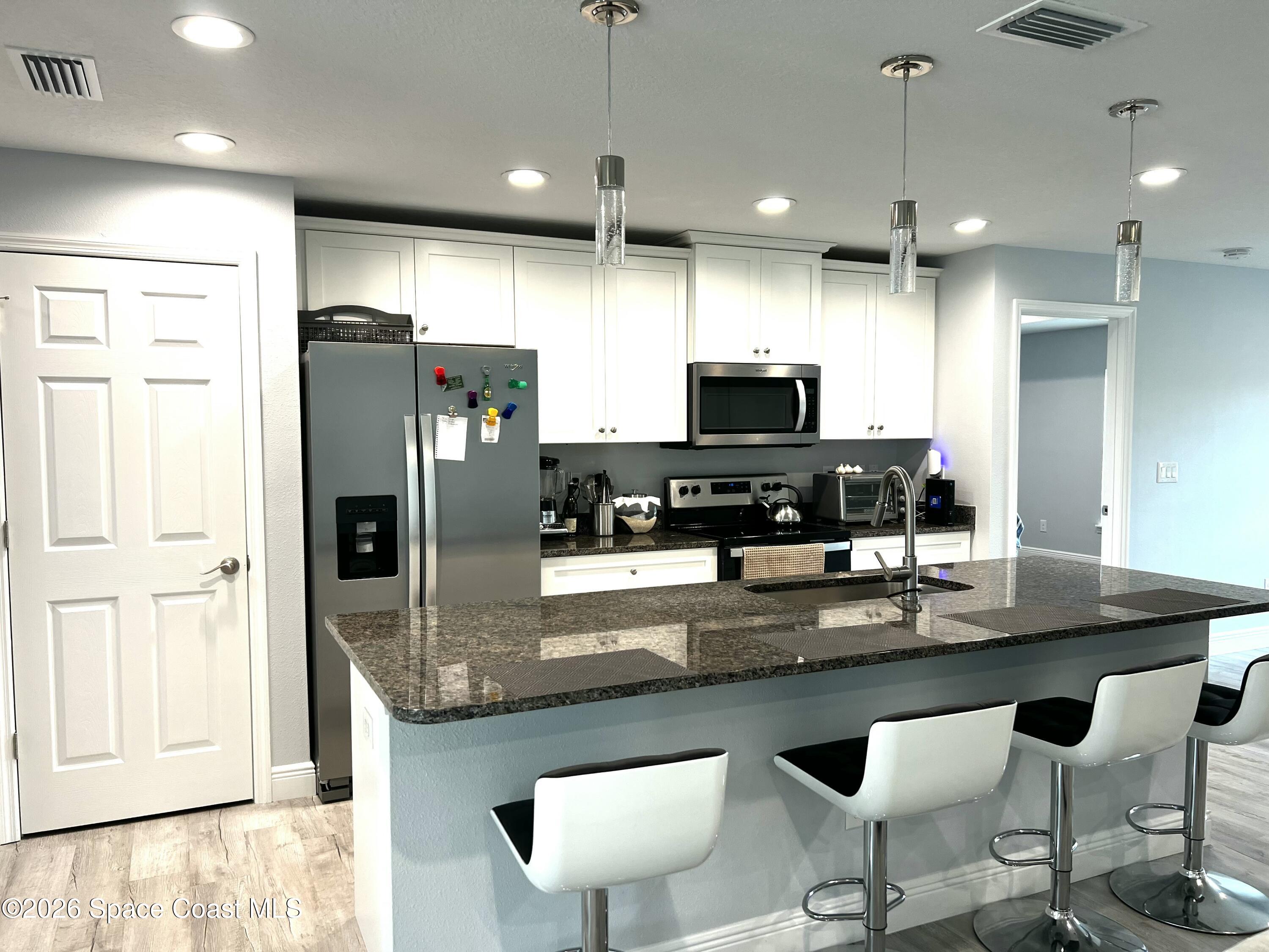 379 Wilton Avenue Southwest Melbourne, FL 32908 - Photo 8 of 26 a kitchen with stainless steel appliances granite countertop a refrigerator a stove a sink a dining table and chairs