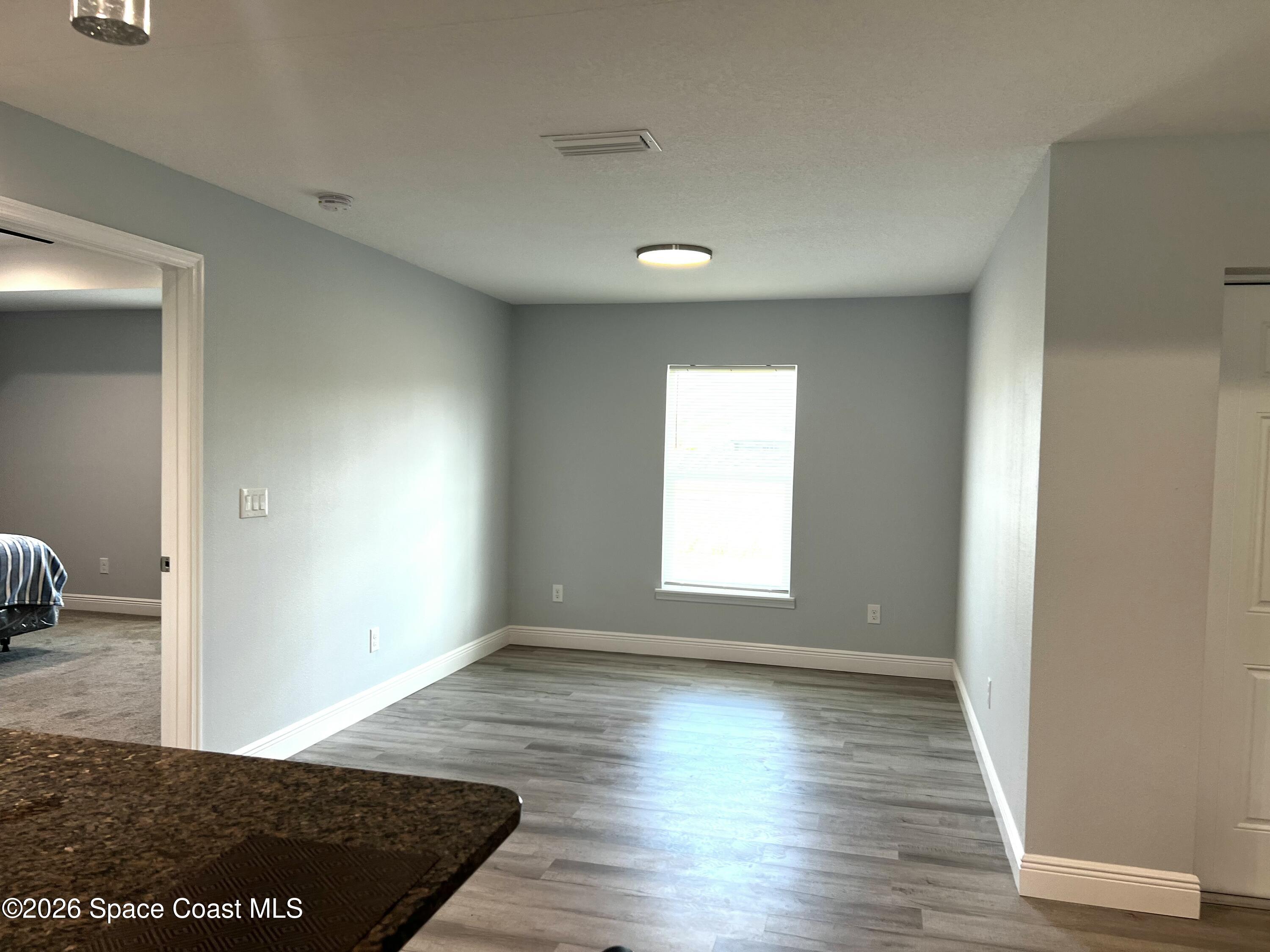 379 Wilton Avenue Southwest Melbourne, FL 32908 - Photo 9 of 26 a view of an empty room with wooden floor and a window
