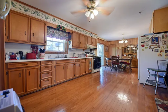 a kitchen with stainless steel appliances wooden floors sink table and chairs