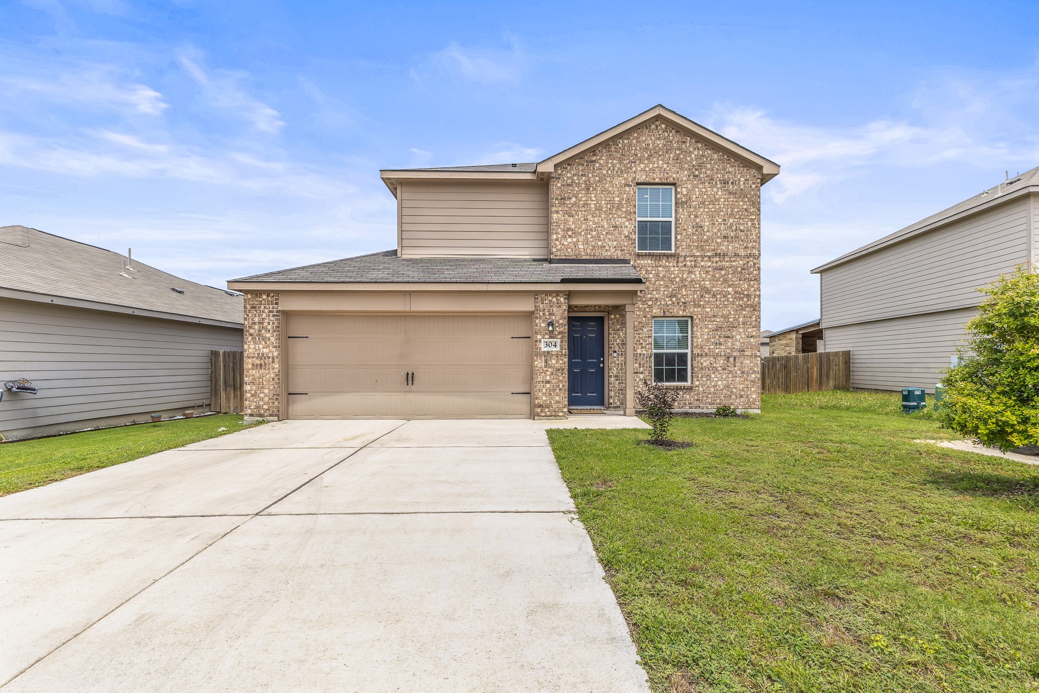 304 Hyacinth Way, Unit #7K Jarrell, TX 76537 - Photo 2 of 26 A classic brick and siding two-story home awaits, complete with an attached garage and a concrete driveway.