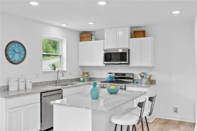 a kitchen with stainless steel appliances granite countertop a sink a stove a microwave a refrigerator and cabinets