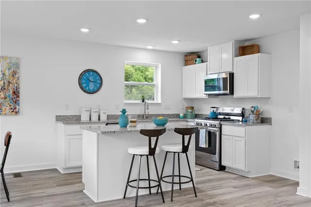 a kitchen with a table chairs a stove a microwave and cabinets