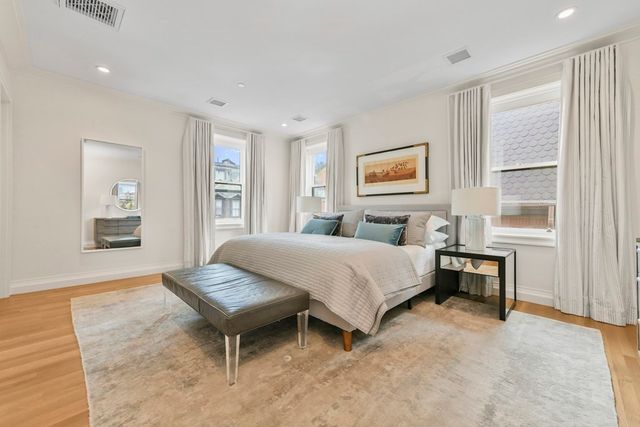 a spacious bedroom with a bed and wooden floor