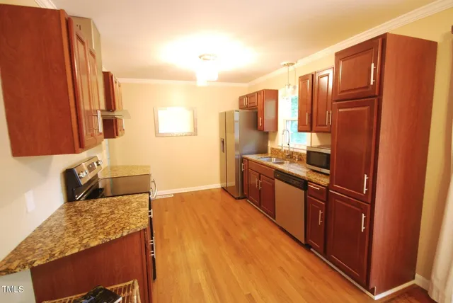 a kitchen with stainless steel appliances granite countertop a refrigerator a sink and wooden cabinets