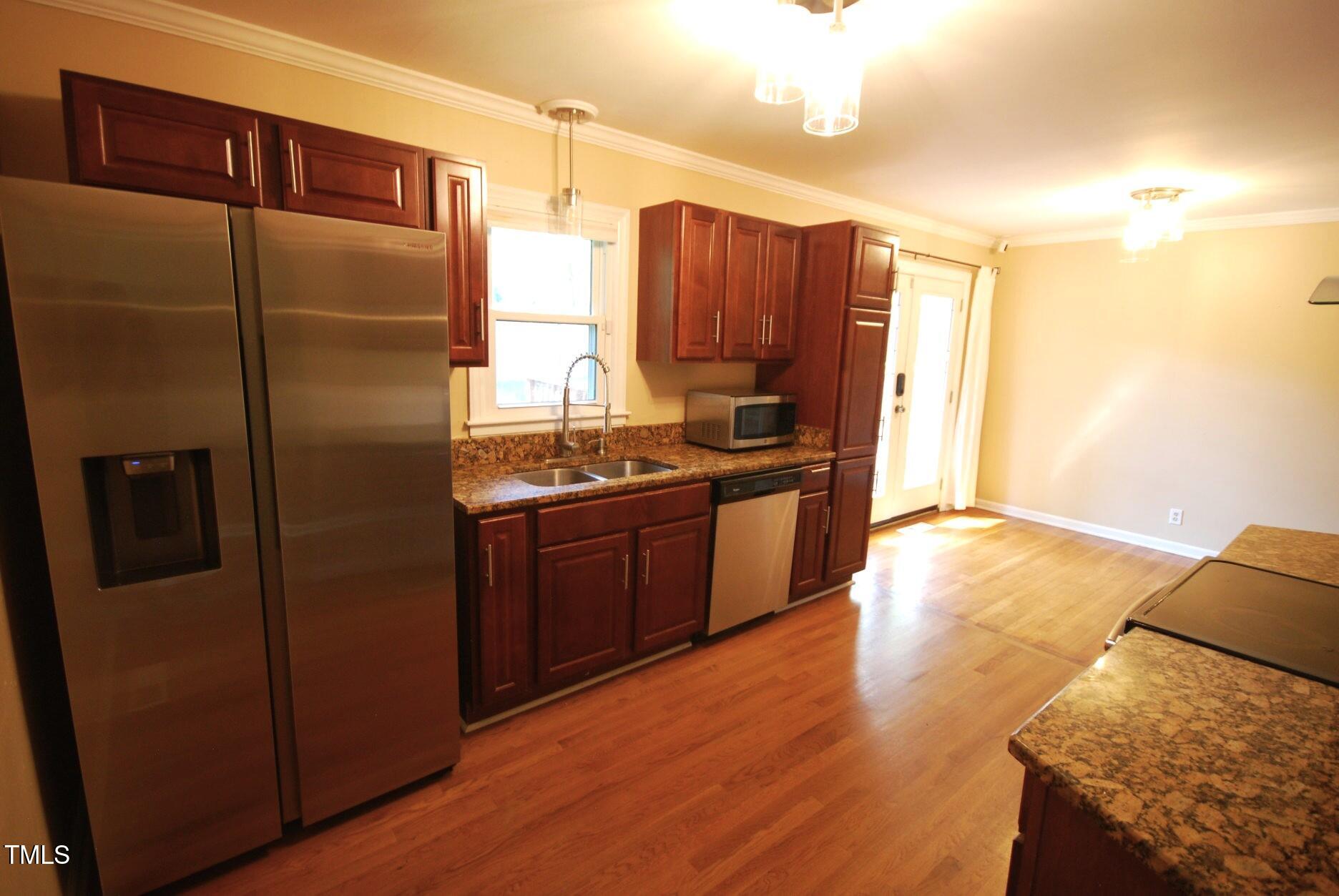 416 Morreene Road Durham, NC 27705 - Photo 7 of 28 a kitchen with stainless steel appliances granite countertop a refrigerator a sink and wooden cabinets