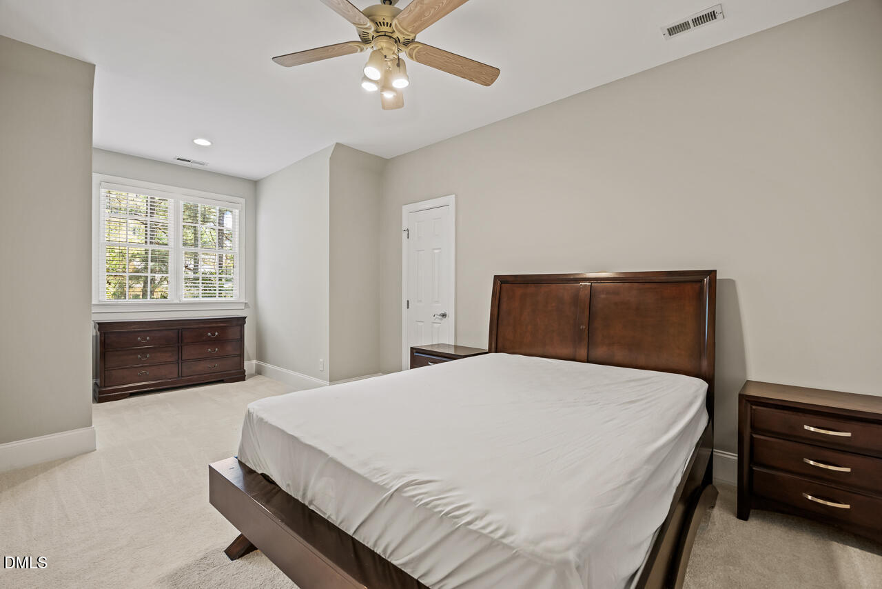 4004 Frontenac Court Apex, NC 27539 - Photo 36 of 61 a bedroom with a large bed and a chandelier