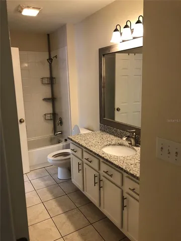 a bathroom with a granite countertop sink a toilet a mirror and shower