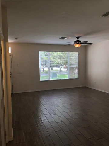 an empty room with wooden floor fan and windows