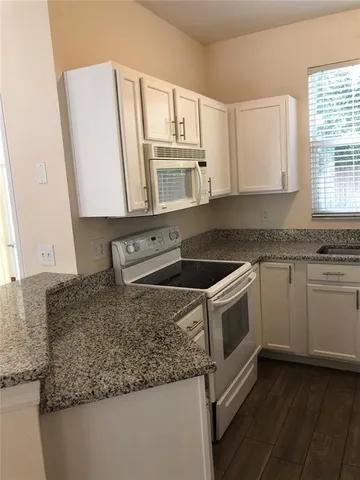 a kitchen with granite countertop a sink a stove and cabinets