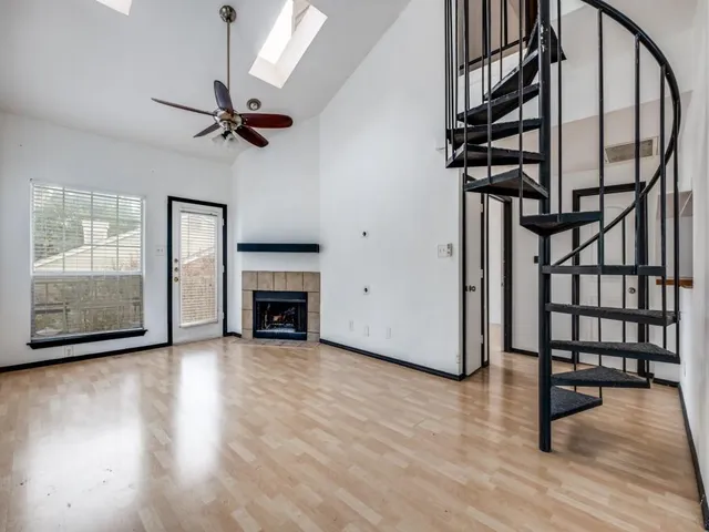 a view of a livingroom with wooden floor a ceiling fan and windows